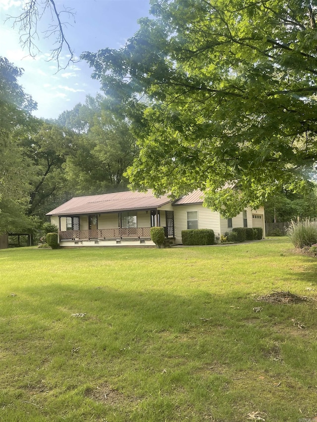 exterior space with covered porch, a yard, and metal roof