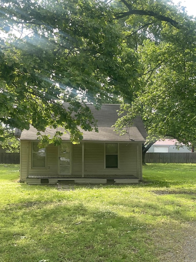 rear view of property featuring a yard, fence, and covered porch