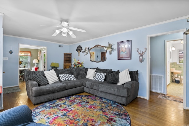 living area with baseboards, a ceiling fan, wood finished floors, and visible vents