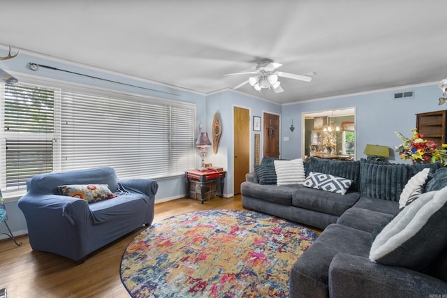living room with crown molding, ceiling fan with notable chandelier, wood finished floors, and a wealth of natural light