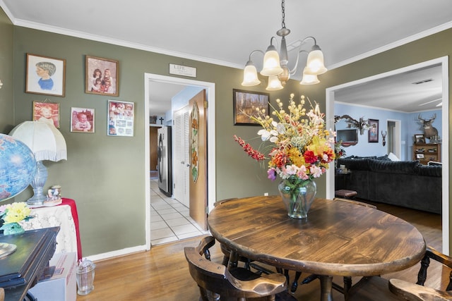 dining room with an inviting chandelier, crown molding, visible vents, and light wood-type flooring