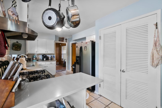 kitchen featuring light tile patterned flooring, a sink, stainless steel fridge with ice dispenser, light countertops, and backsplash