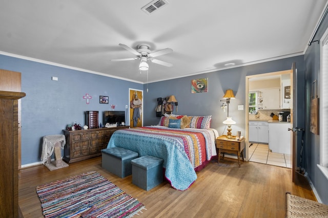 bedroom with visible vents, light wood-style floors, crown molding, and ceiling fan