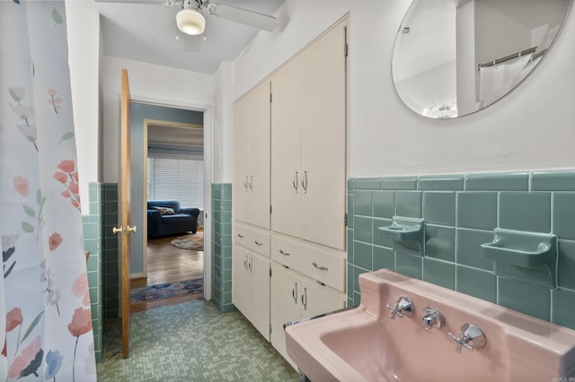 full bath with tile walls, a ceiling fan, wainscoting, and tile patterned floors