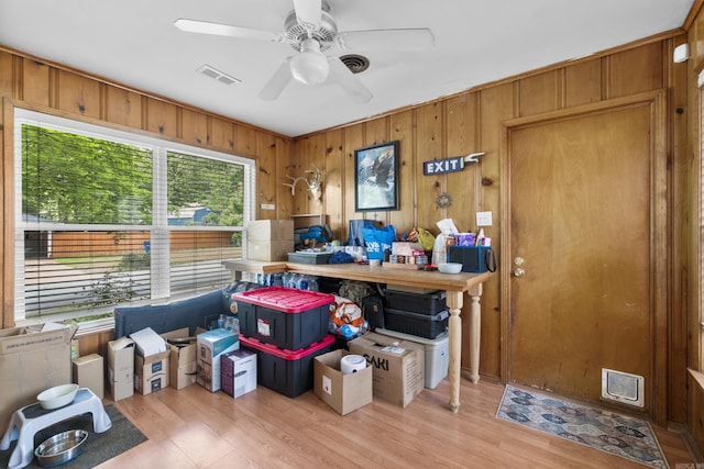 misc room featuring visible vents, a ceiling fan, light wood-style flooring, and wooden walls