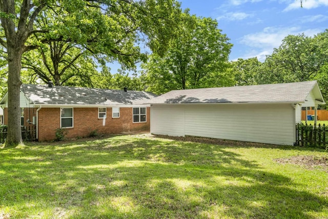 rear view of house featuring fence, a shingled roof, a yard, and brick siding