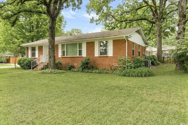 single story home featuring brick siding, fence, central air condition unit, and a front yard