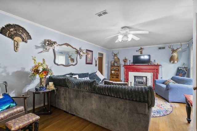 living room with ornamental molding, wood finished floors, and visible vents