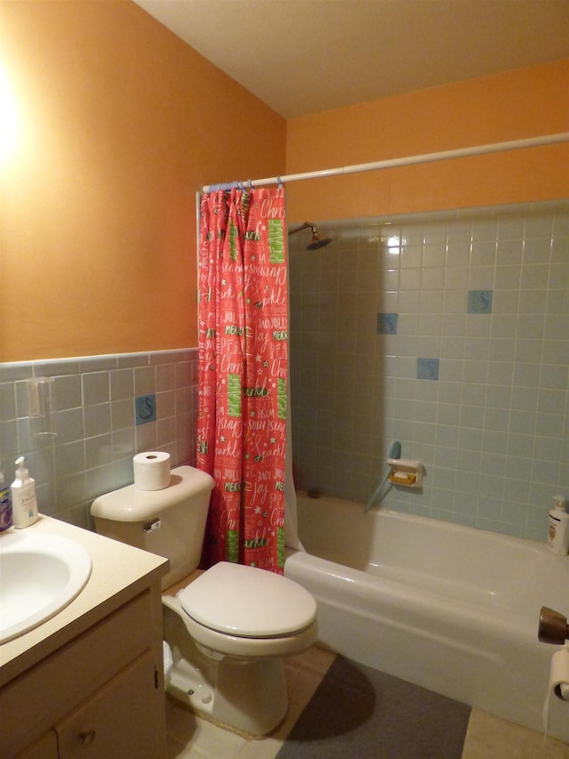 full bath with vanity, wainscoting, toilet, tile walls, and shower / bath combo