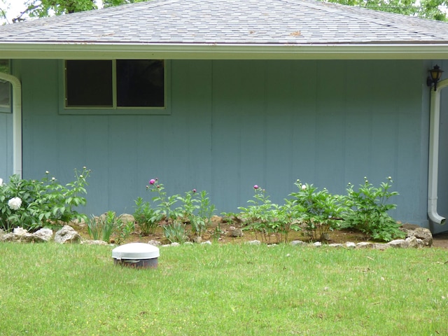 view of side of property with a yard and a shingled roof