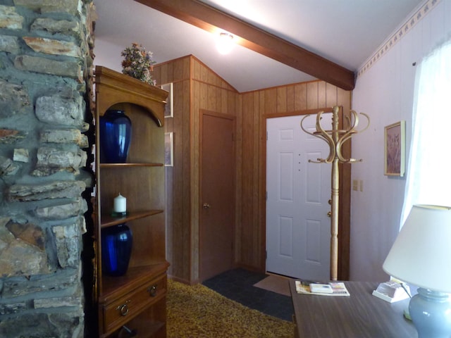 carpeted entrance foyer with wooden walls and vaulted ceiling with beams