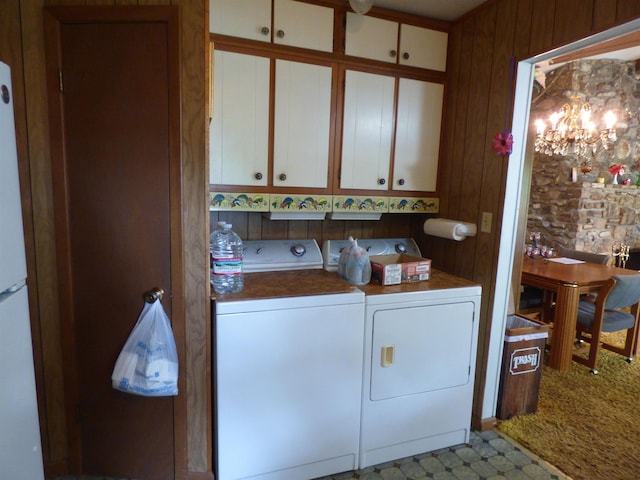 washroom with cabinet space, wood walls, light colored carpet, and washing machine and dryer