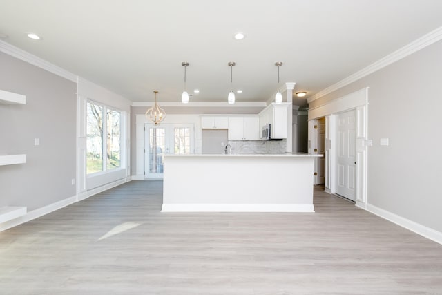 2919 Martel Ave, Little Rock, AR 72206 - kitchen with backsplash, white cabinets, stainless steel microwave, a chandelier, and ornamental molding