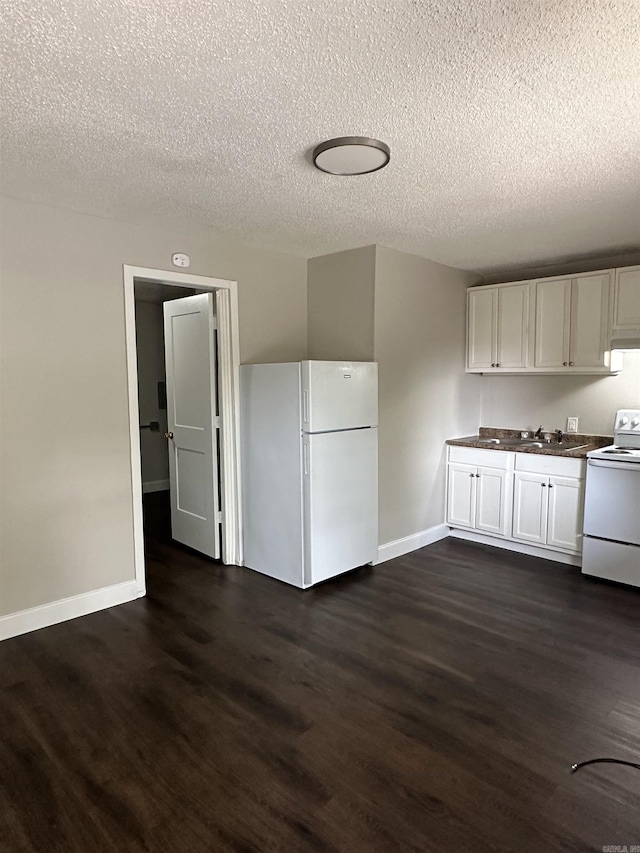 kitchen with white appliances, a textured ceiling, dark wood-style floors, and baseboards
