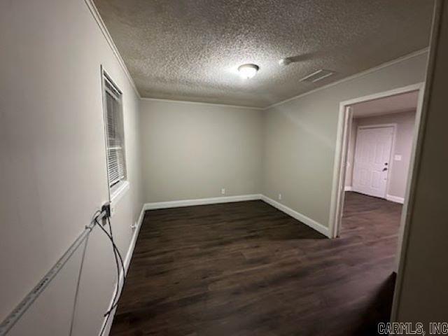 unfurnished room with crown molding, a textured ceiling, dark wood finished floors, and baseboards