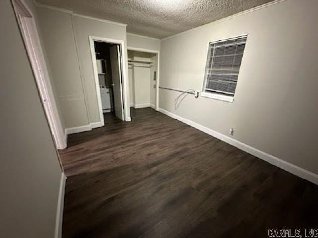 unfurnished bedroom featuring baseboards, a closet, dark wood-style flooring, and a textured ceiling