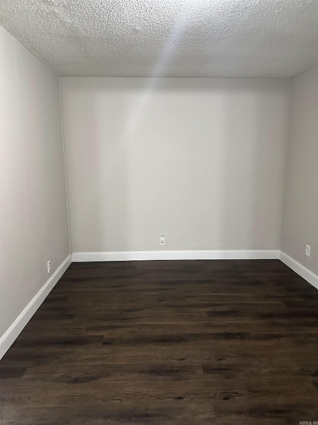 spare room with baseboards, dark wood finished floors, and a textured ceiling