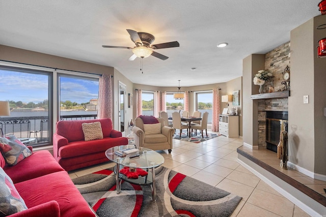 101 Long Island Dr, Hot Springs, AR 71913 - living area featuring ceiling fan, a stone fireplace, light tile patterned floors, baseboards, and a water view