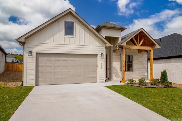 view of front facade with a front lawn, stone siding, a shingled roof, board and batten siding, and concrete driveway