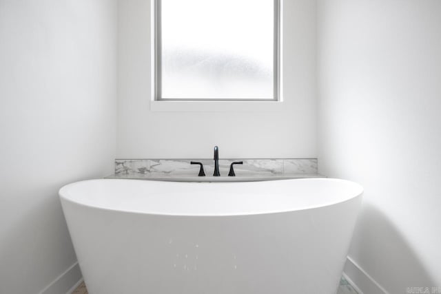 full bath featuring a freestanding tub and baseboards