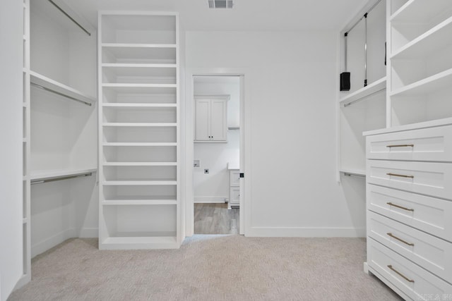 walk in closet featuring visible vents and light carpet