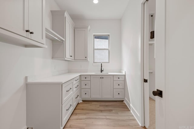laundry room with recessed lighting, a sink, and light wood finished floors