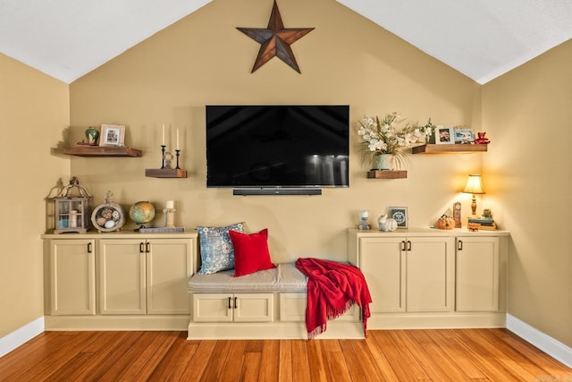 living room featuring baseboards, wood finished floors, and lofted ceiling