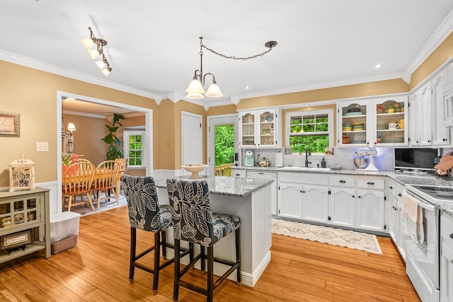 kitchen with a kitchen island, white electric stove, crown molding, a breakfast bar, and white cabinetry