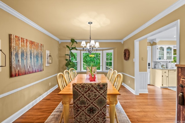 dining room with crown molding, an inviting chandelier, and light wood-style flooring