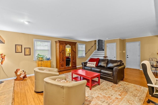 living area featuring light wood-style floors, stairs, baseboards, and a wealth of natural light