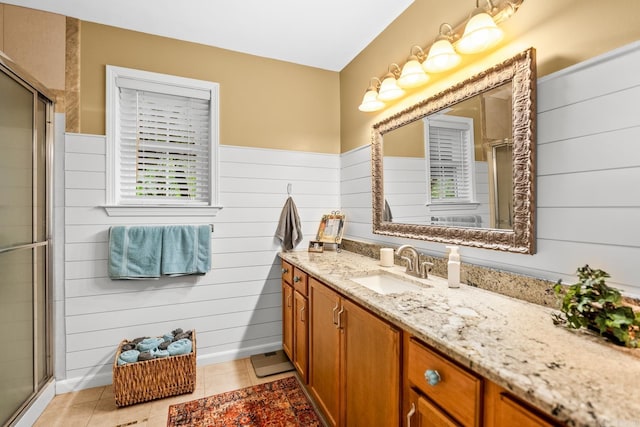 full bath featuring vanity, tile patterned flooring, a stall shower, and wood walls