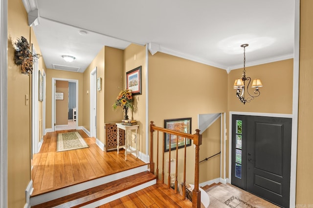entrance foyer featuring wood-type flooring, crown molding, stairs, an inviting chandelier, and baseboards