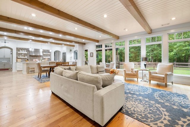 living room featuring a healthy amount of sunlight, beamed ceiling, light wood-style floors, and recessed lighting