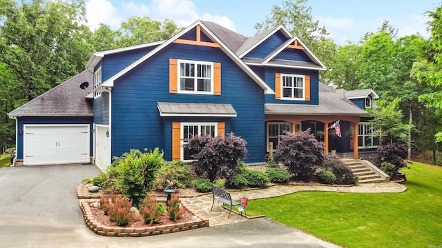 craftsman-style house with a garage, a standing seam roof, a front yard, and aphalt driveway