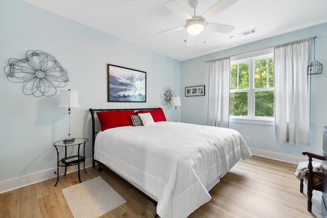 bedroom with a ceiling fan, baseboards, visible vents, and wood finished floors