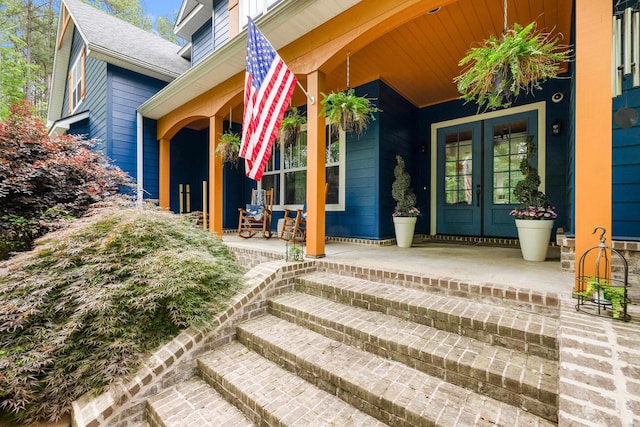 view of exterior entry featuring french doors and covered porch