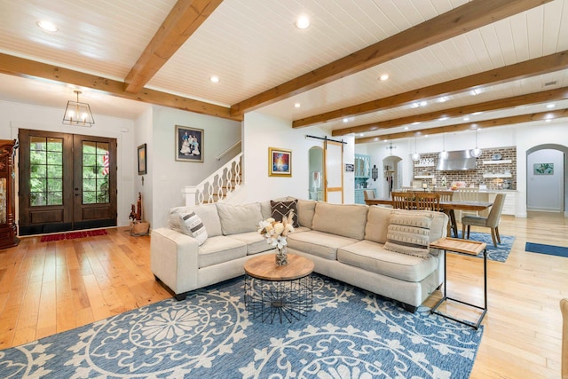 living area with stairs, beam ceiling, recessed lighting, arched walkways, and light wood finished floors
