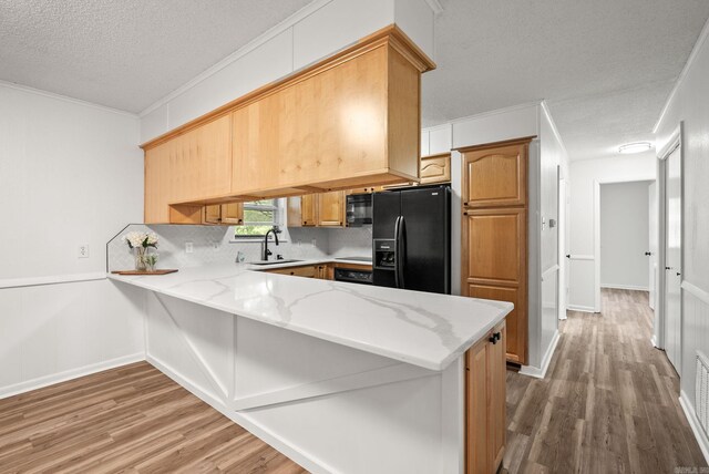 22 Colony Rd, Little Rock, AR 72227 - kitchen with a sink, light wood-style floors, a textured ceiling, a peninsula, and black appliances