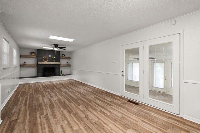 22 Colony Rd, Little Rock, AR 72227 - unfurnished living room with visible vents, wood finished floors, a textured ceiling, a ceiling fan, and a skylight