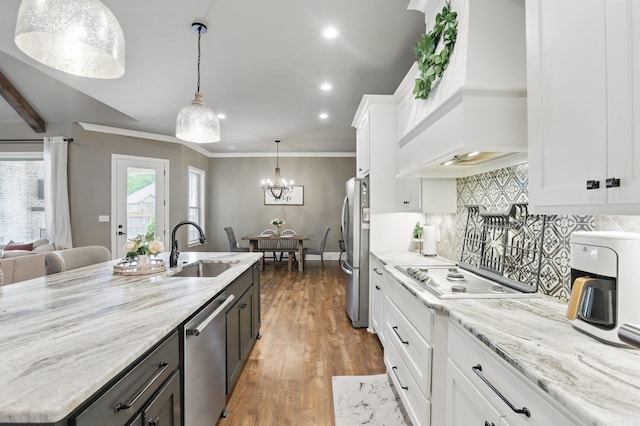 kitchen featuring light stone countertops, appliances with stainless steel finishes, a sink, white cabinetry, and custom exhaust hood