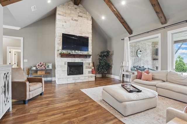 living room featuring a fireplace, baseboards, wood finished floors, beamed ceiling, and visible vents