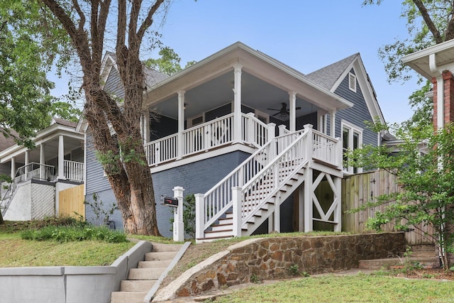 exterior space featuring brick siding, a shingled roof, ceiling fan, and stairway