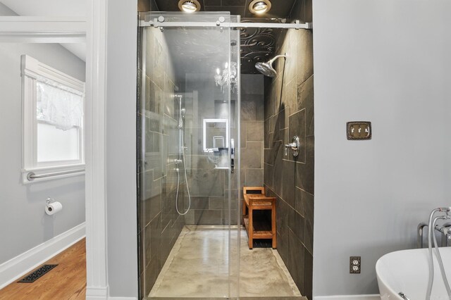 full bath featuring visible vents, baseboards, a freestanding bath, and a stall shower