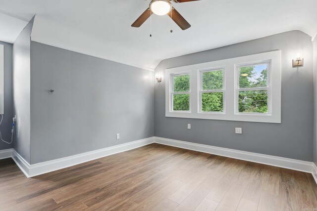 spare room with baseboards, ceiling fan, wood finished floors, and lofted ceiling