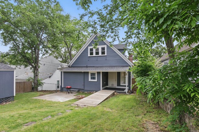 back of property featuring a yard, fence, a shingled roof, and a patio area