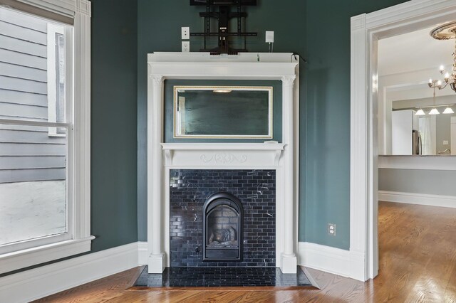 interior details with freestanding refrigerator, wood finished floors, a fireplace, baseboards, and a notable chandelier