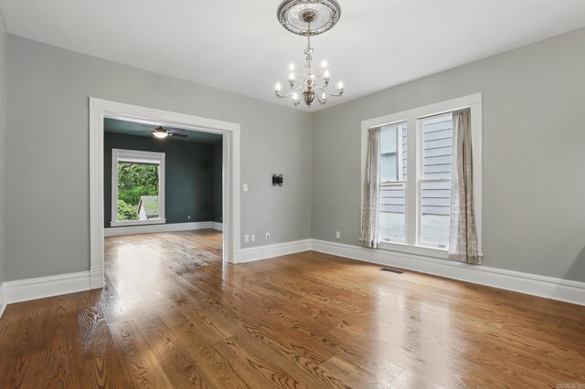 unfurnished dining area with a chandelier, baseboards, visible vents, and wood finished floors