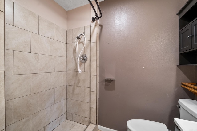 bathroom featuring toilet, baseboards, and tiled shower
