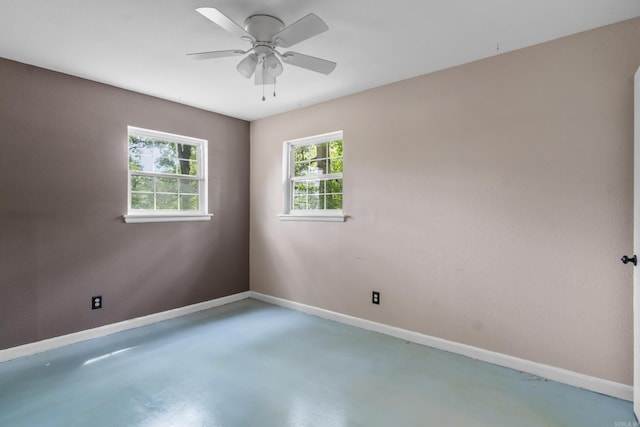 empty room with concrete flooring, baseboards, and ceiling fan