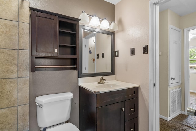 bathroom featuring visible vents, a textured wall, toilet, and vanity